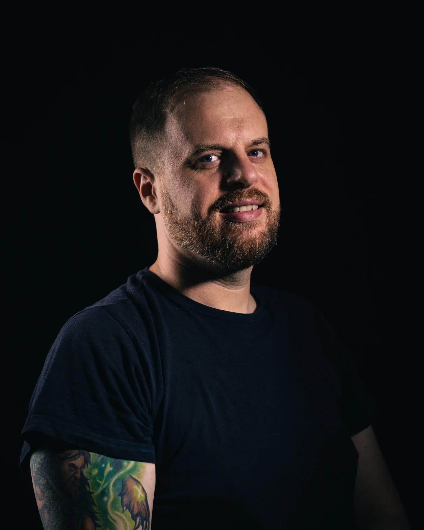 Dominik Süß im dunklen T-Shirt vor einem dunklen Hintergrund.